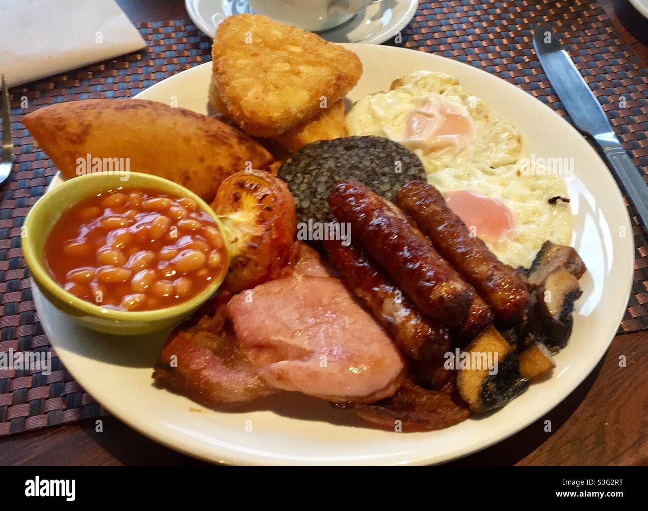Cooked Scottish breakfast on a plate with haggis, beans, bacon, fried