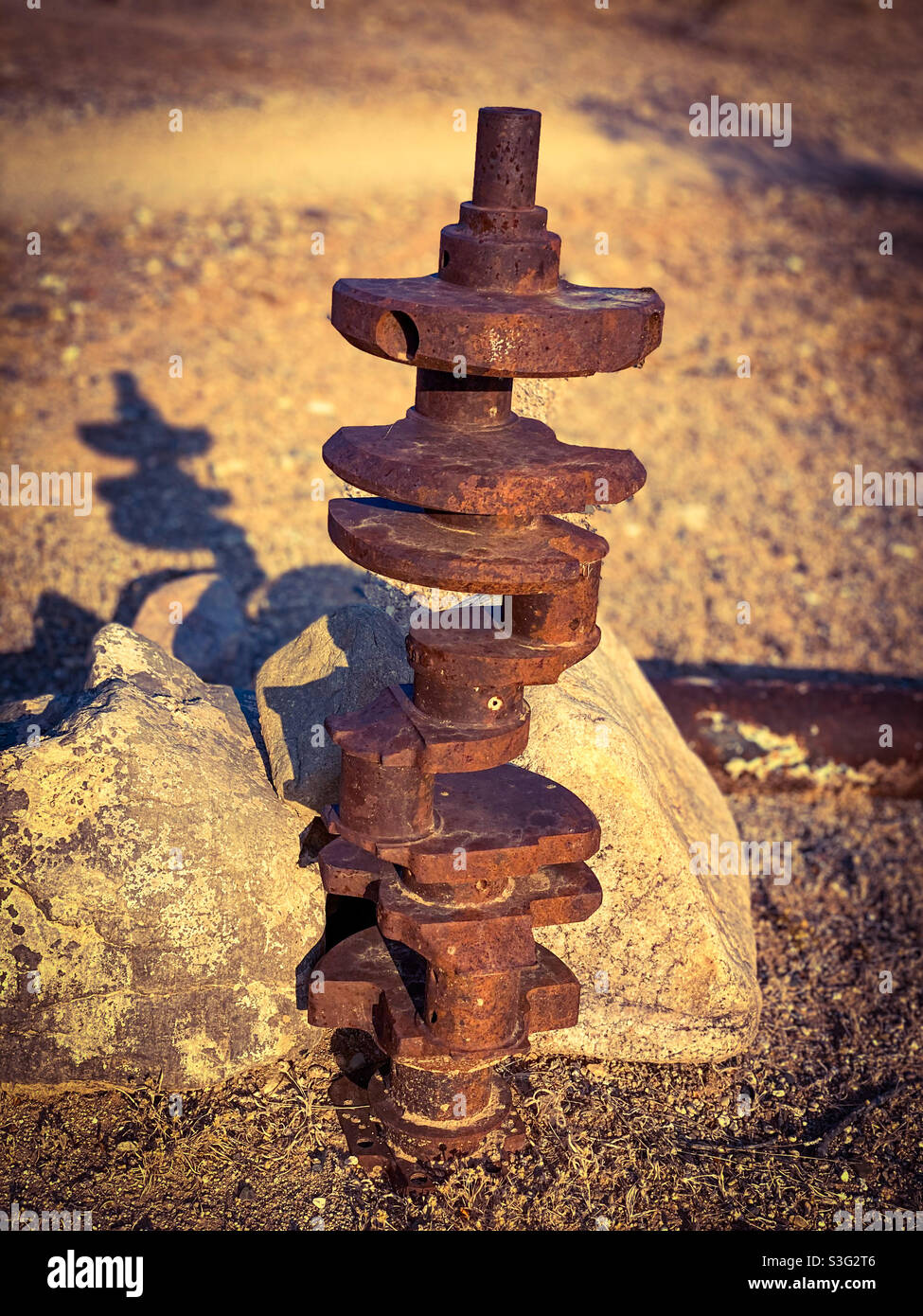 An old rusty crankshaft standing on end out in the desert Stock Photo