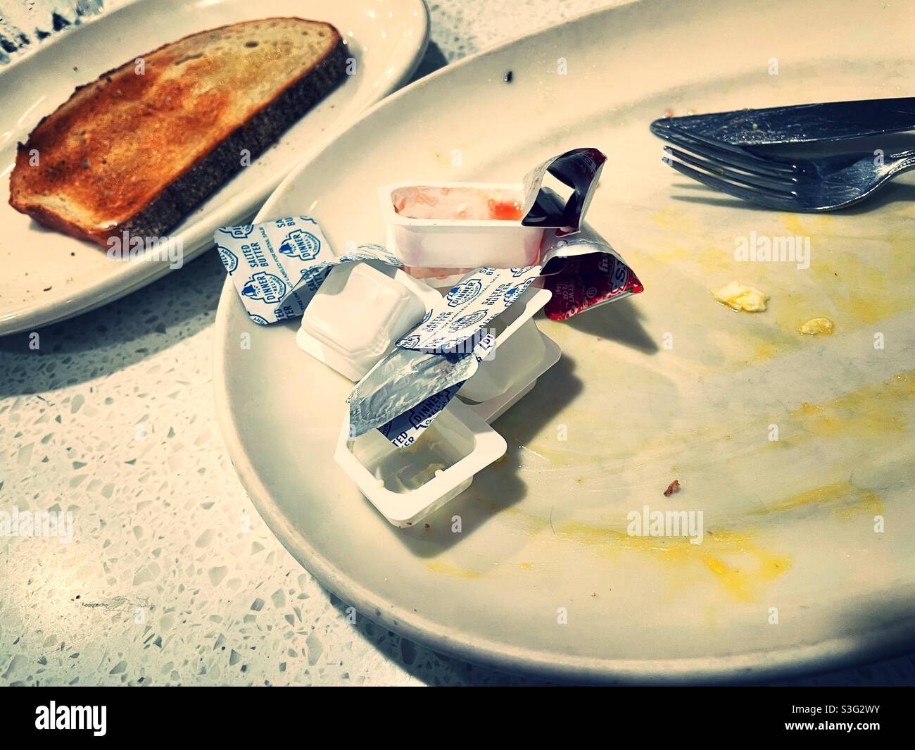 Empty jelly and butter wrappers on an empty plate after a breakfast meal at a diner in New York City, USA - Smartphone Captured Stock Image