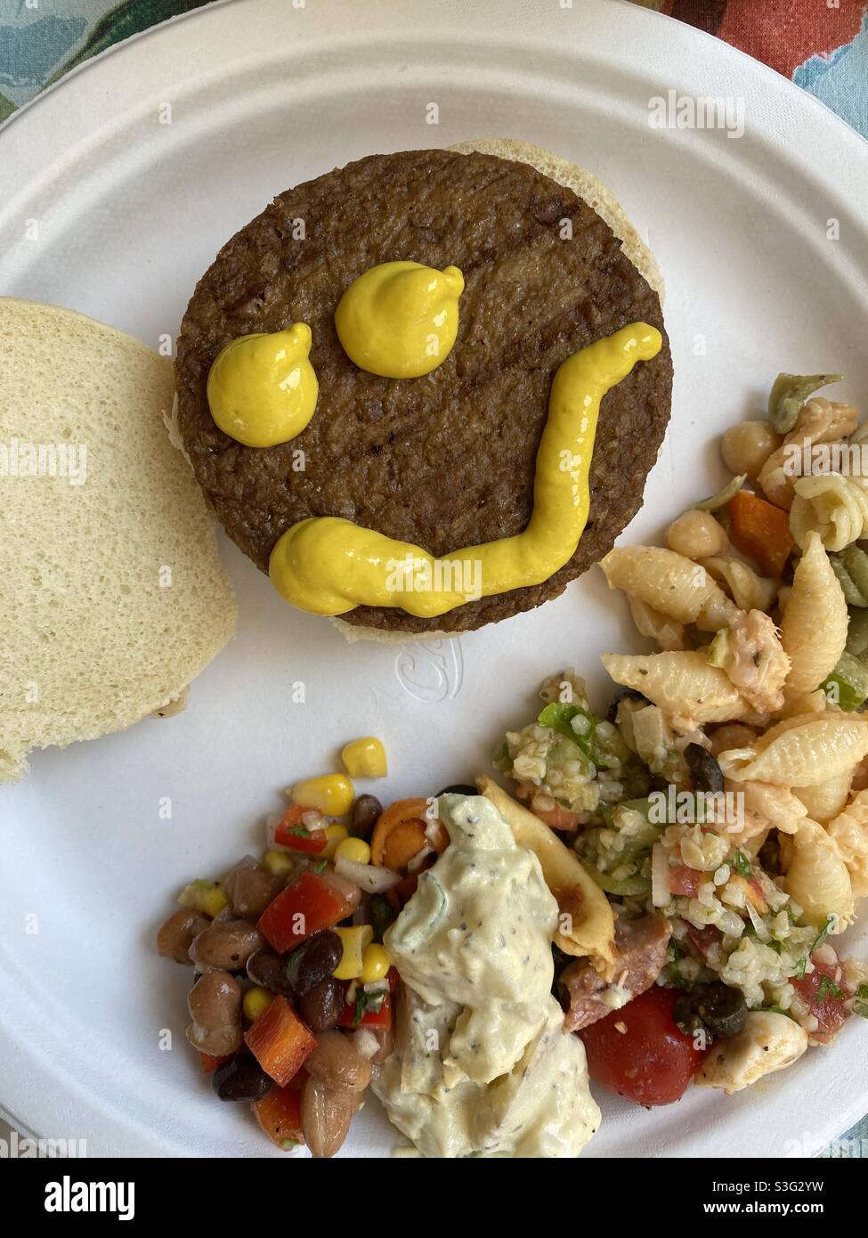 Mustard smiley face on a veggie burger, summer cookout. - Smartphone Captured Stock Image
