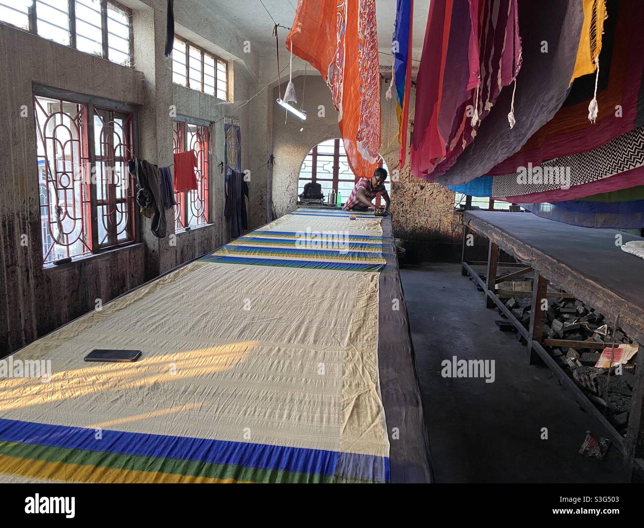 A man is colour dying in a sari making factory - Smartphone Captured Stock Image