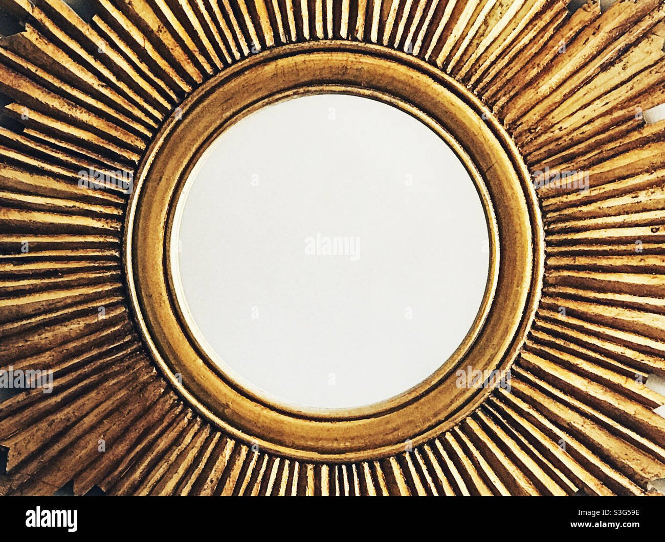 Closeup of a gold sun-shaped circular mirror with no reflection. - Smartphone Captured Stock Image