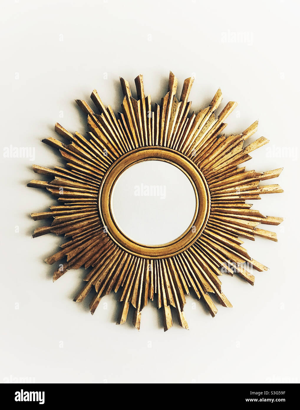 Sun-shaped golden mirror with nothing reflected in it. - Smartphone Captured Stock Image