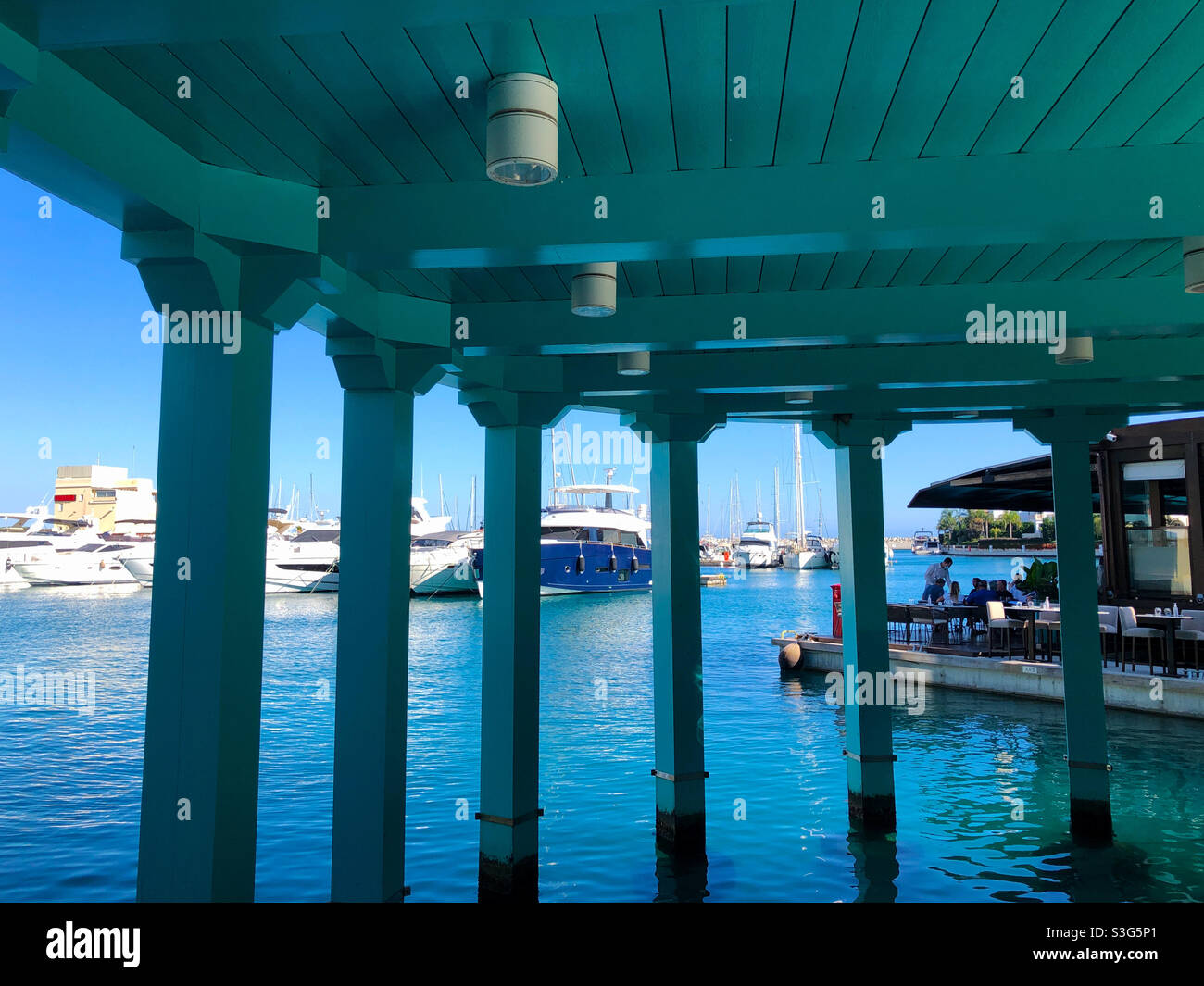 Limassol Marina and an outdoors restaurant area seen from under a boardwalk. - Smartphone Captured Stock Image