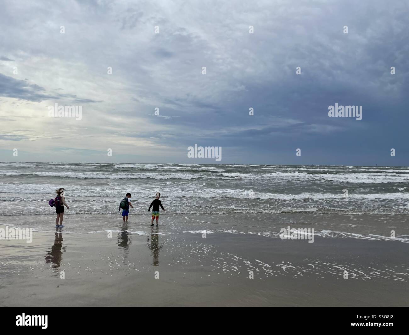 Kids with hiking gear on the beach of Mustang Island State Park in Texas Stock Photo