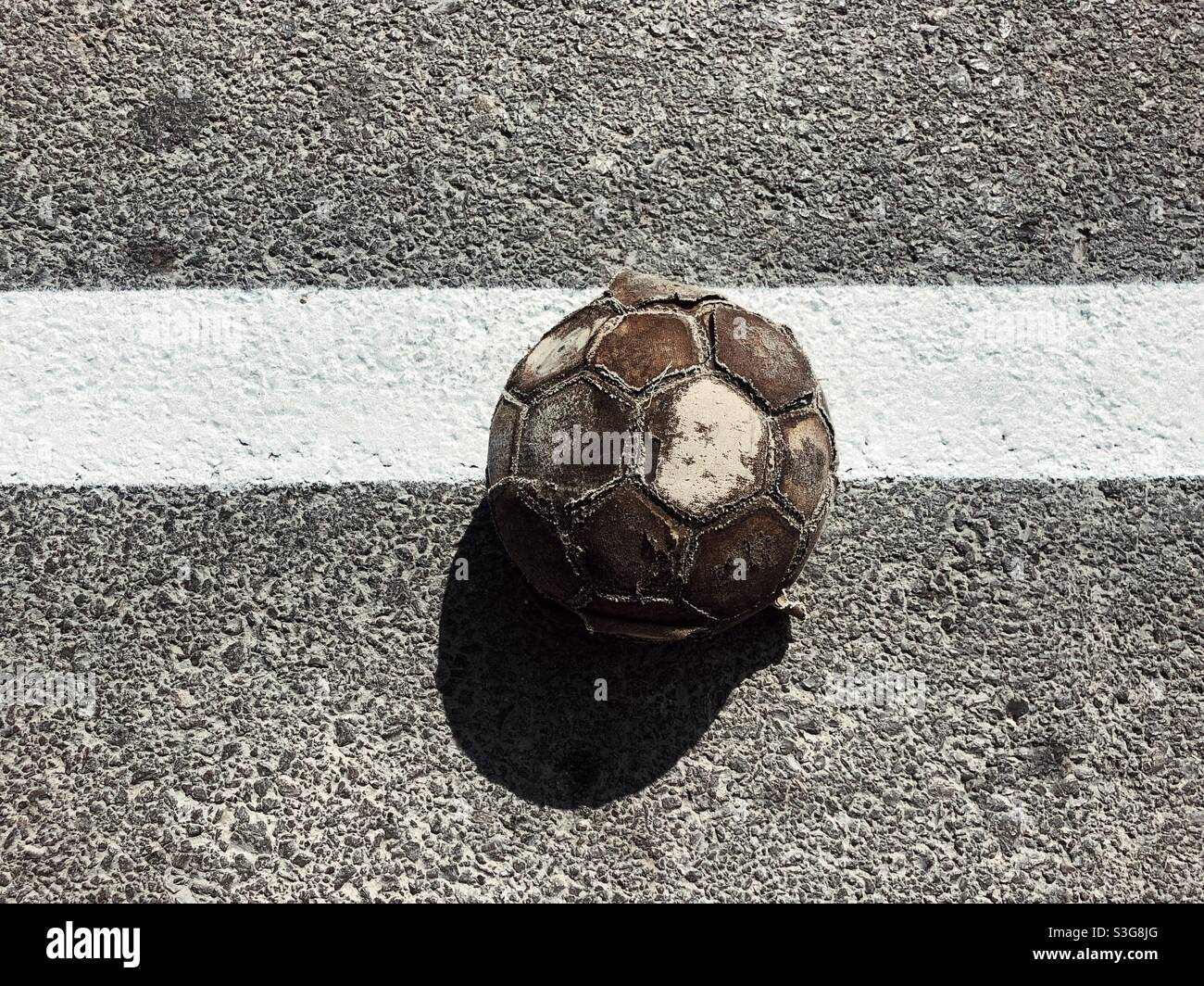 Decayed football on asphalt - Smartphone Captured Stock Image