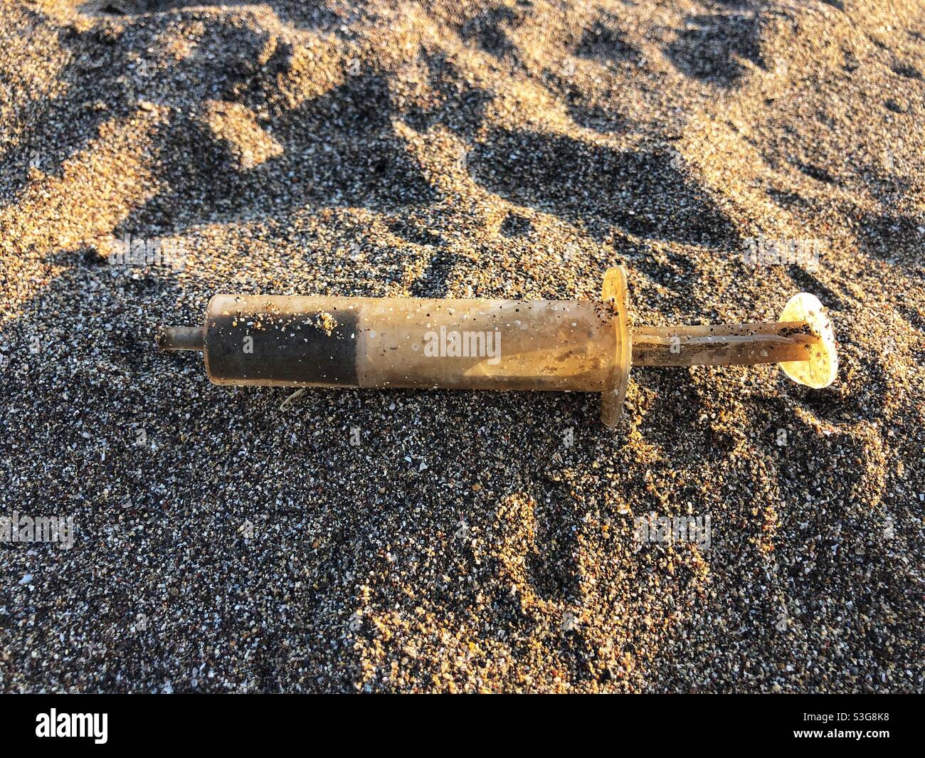 Old rusty syringe on sand Stock Photo