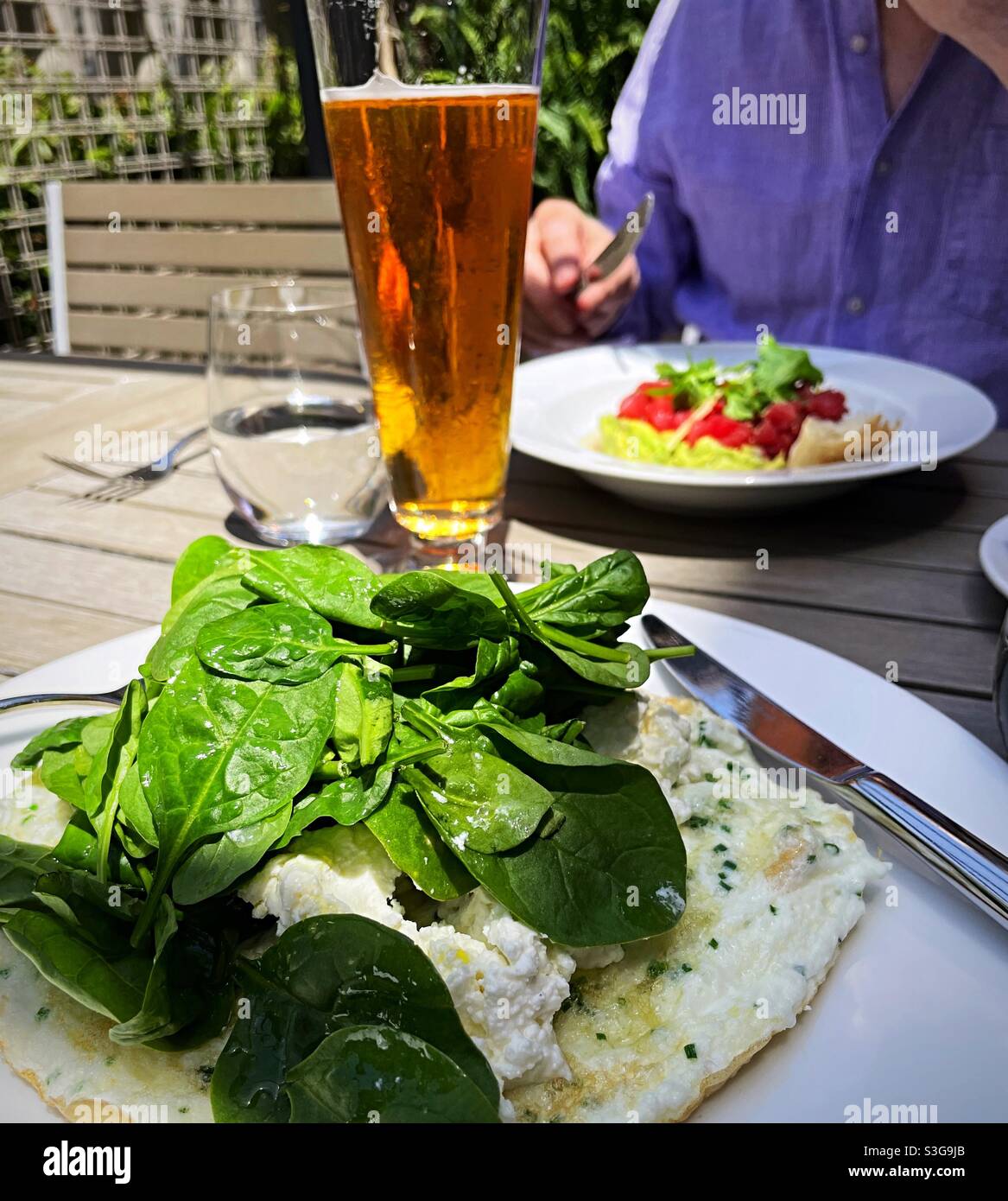 Close up of a gourmet lunch and table featuring tuna tartare, egg white omelette and a tall Pilsner glass of beer, 2021, New York City, USA - Smartphone Captured Stock Image