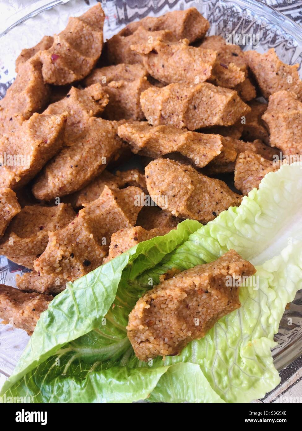 Turkish vegan dish cig kofte of which main ingredient is bulgur wheat. It’s served with lettuce and other vegetables Stock Photo