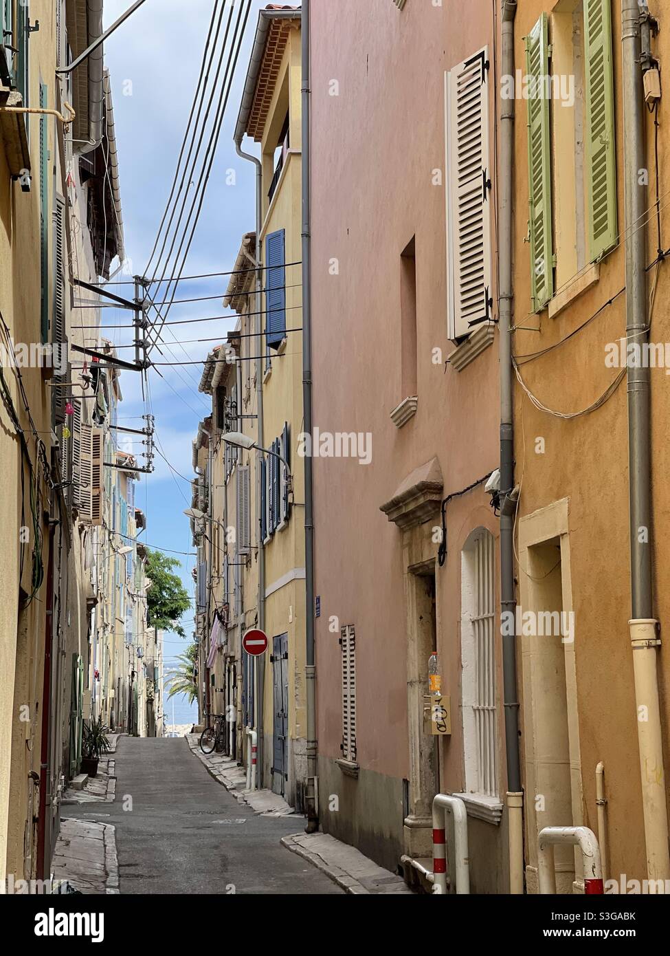 A narrow street leading to the waterfront bordered by old village houses downtown La Ciotat, near Marseille, Bouches-du-Rhône, Provence-Alpes-Côte d'Azur, south of France - Smartphone Captured Stock Image