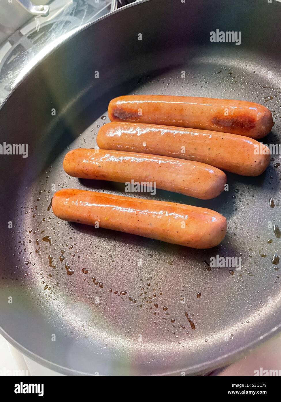 Four bratwurst sausages frying in a skillet - Smartphone Captured Stock Image