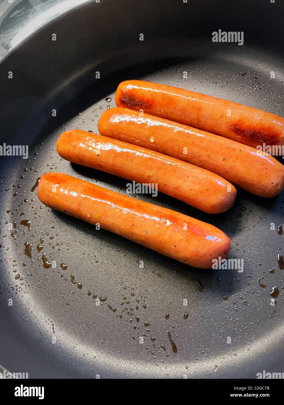 Close up of bratwurst cooking in a red hot skillet - Smartphone Captured Stock Image