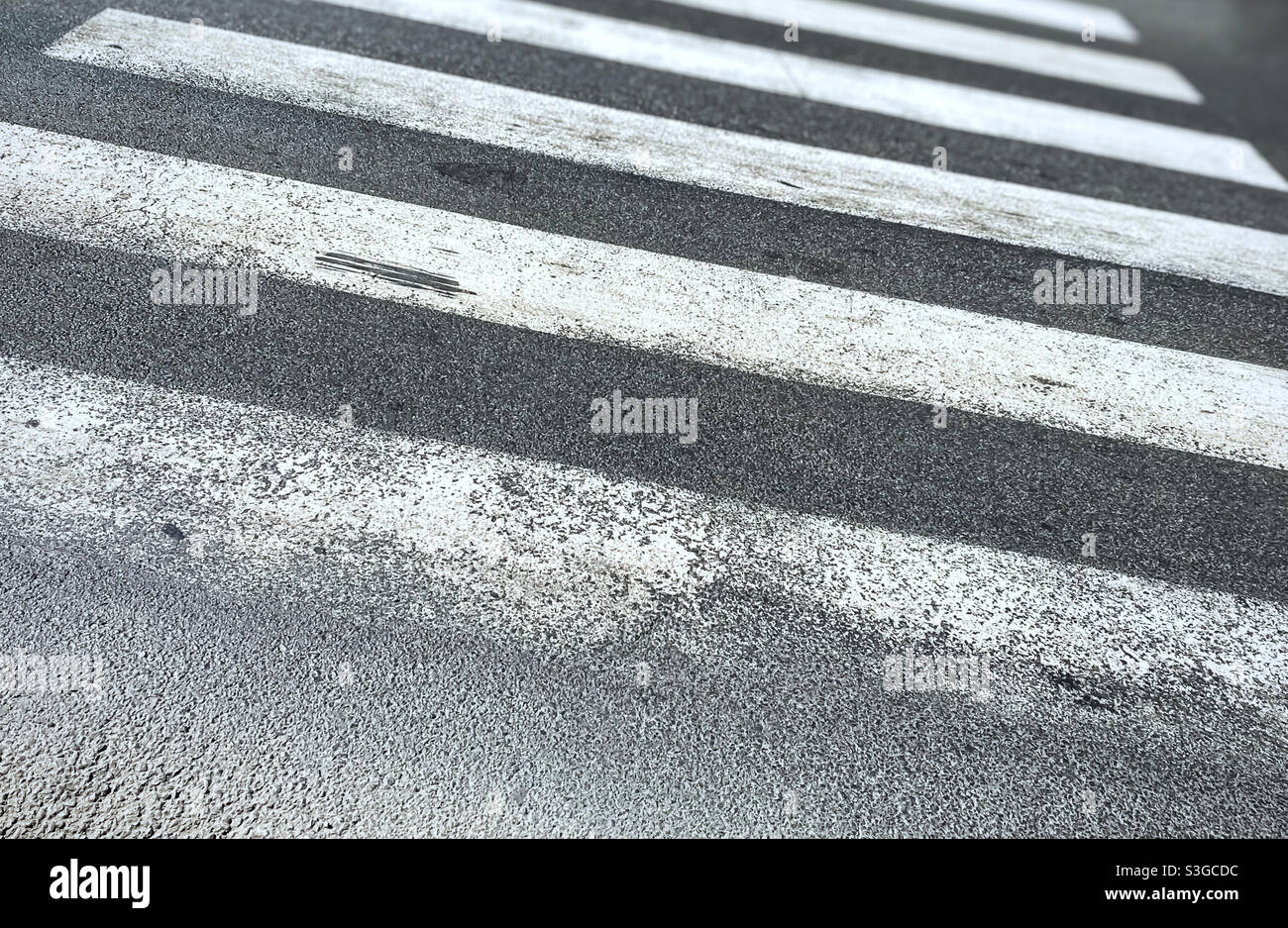 pedestrian crossing of a street with worn and ruined asphalt. Zebra crossing in a European city. Road signs and pedestrian crossing. Road safety - Smartphone Captured Stock Image