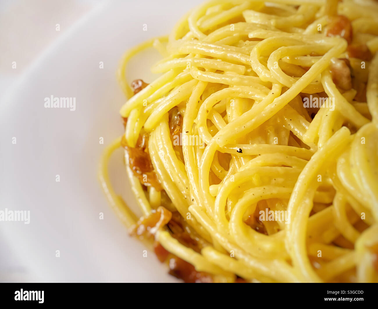 Close up of cooked spaghetti with carbonara sauce. Traditional recipe of Italian cuisine. Cooked pasta with yellow carbonara egg yolk sauce - Smartphone Captured Stock Image