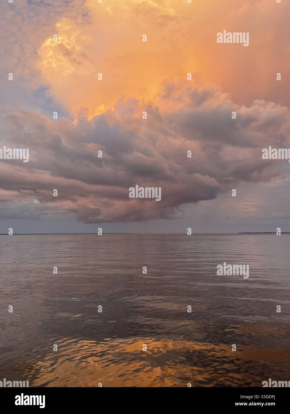 Dramatic large stormy sunset clouds reflecting onto bay water Stock ...