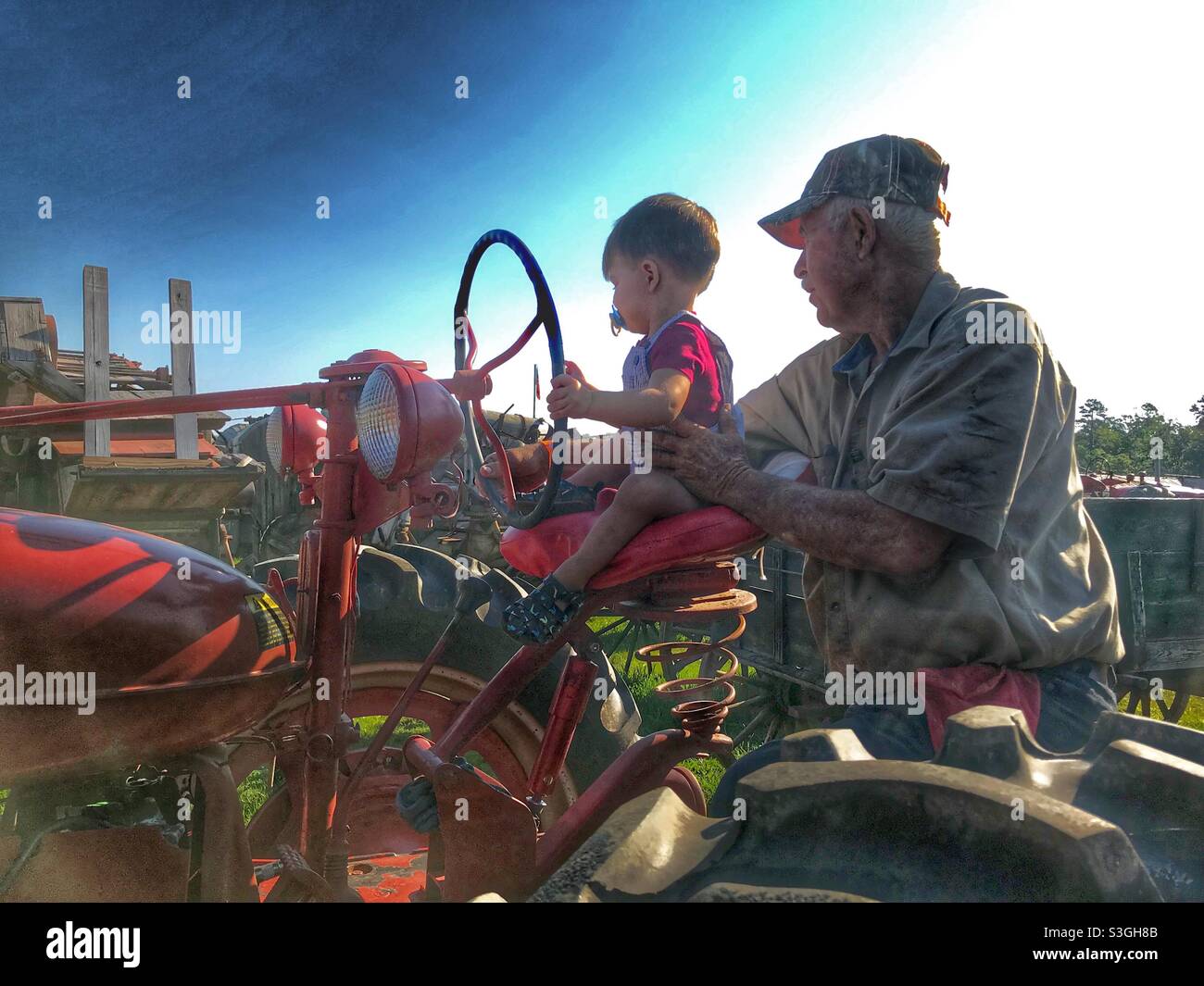 PawPaw and grandson riding a tractor at 4th of July celebration - Smartphone Captured Stock Image
