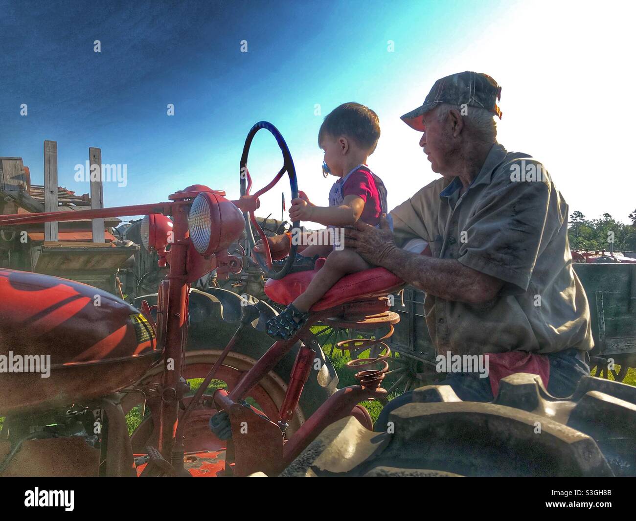 PawPaw and grandson riding a tractor at 4th of July celebration Stock Photo