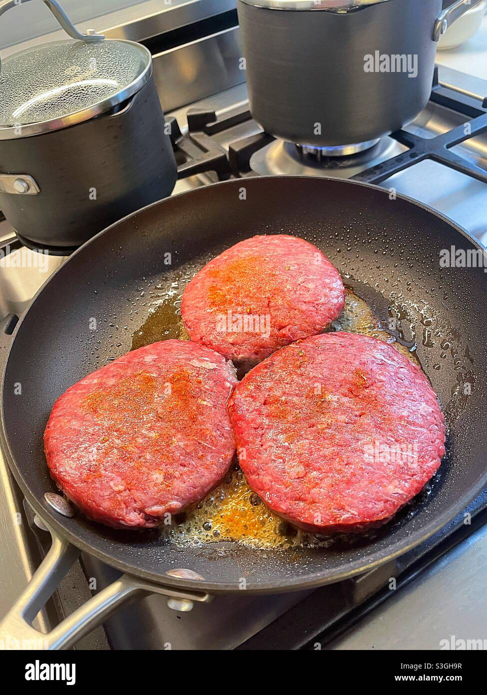 Hamburgers frying in a skillet on a residential stove top, USA - Smartphone Captured Stock Image