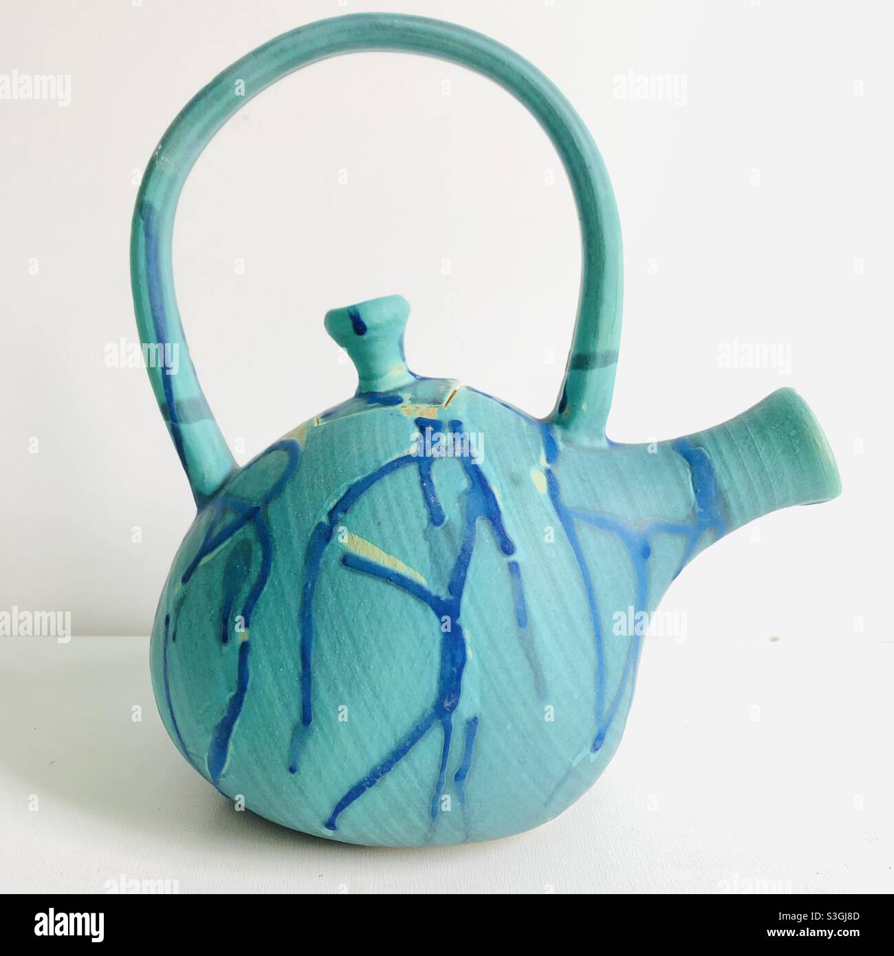 Handmade teapot made of turquoise teal and blue clay ready for getting together Stock Photo