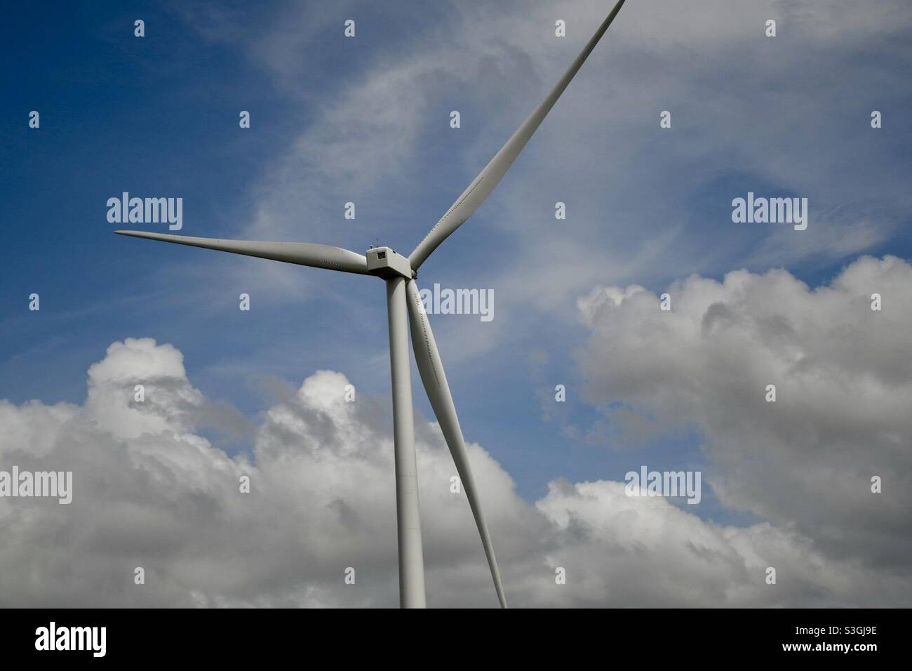 Wind turbine against a blue sky with clouds Stock Photo