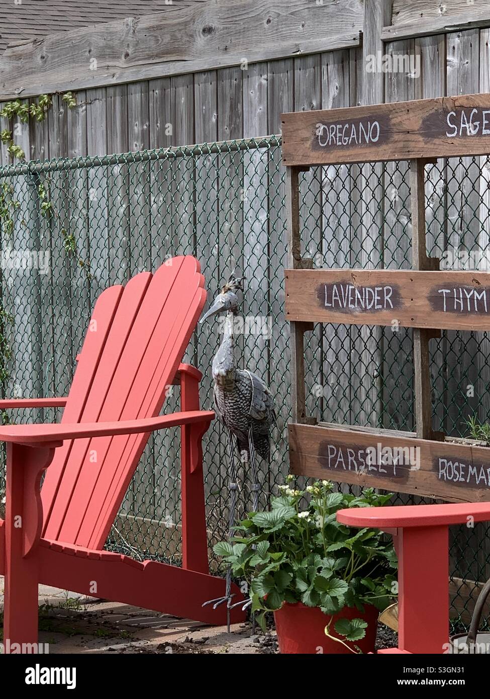 Artistic metal bird standing between a red chair and spice rack - Smartphone Captured Stock Image Artistic metal bird standing between a red chair and spice rack - Smartphone Captured Stock Image