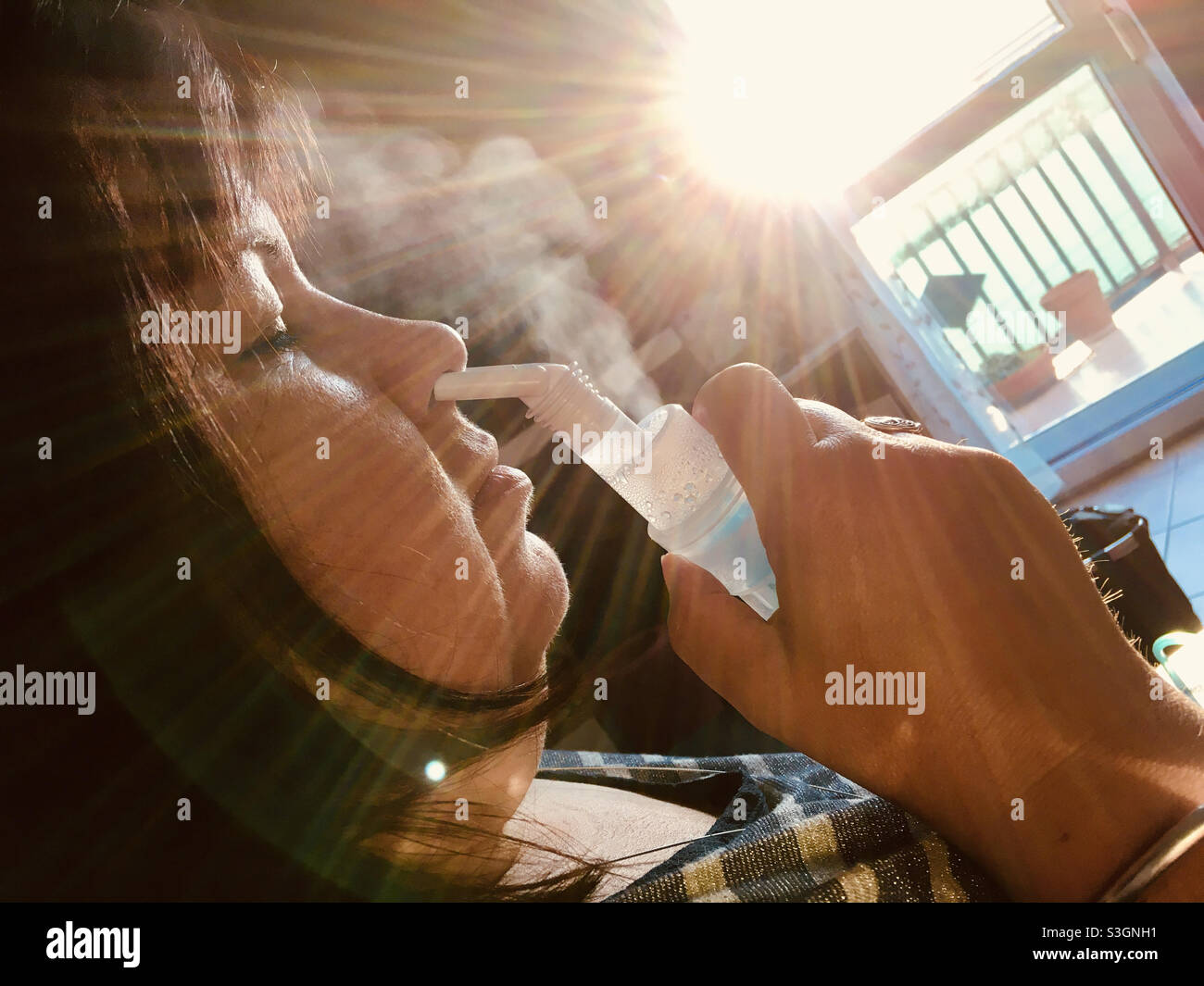Woman using inhaler with salty water at home - Smartphone Captured Stock Image