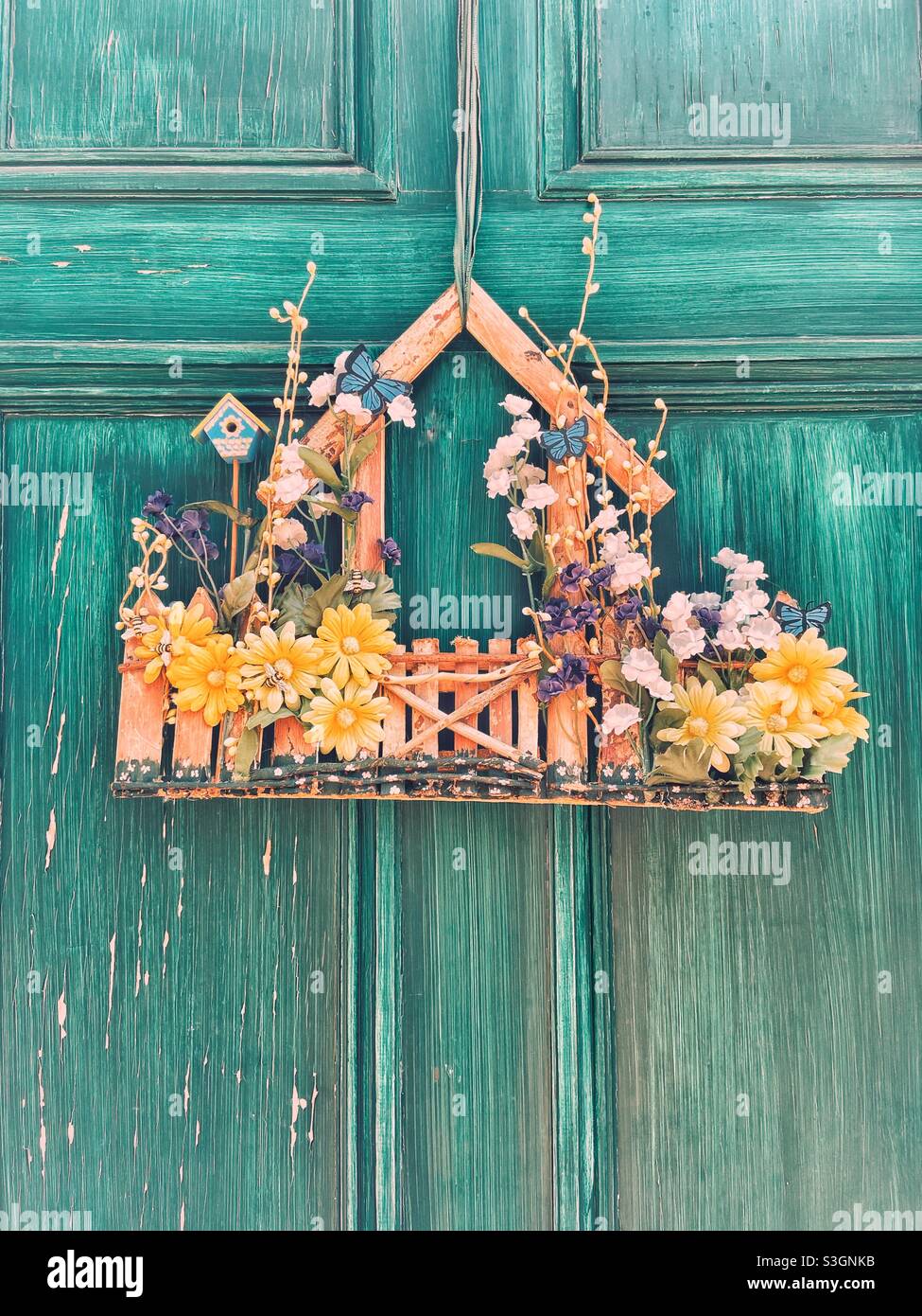 Charming spring summer decoration on a distressed green decorated front door. Vintage feel. - Smartphone Captured Stock Image