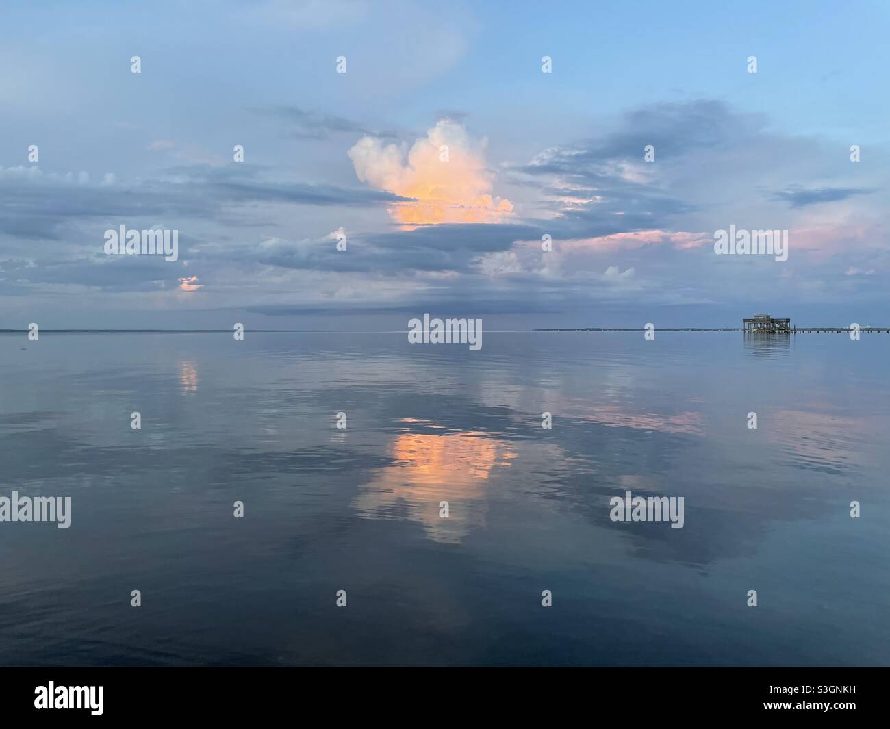 Colorful sunset clouds reflecting onto calm bay water Stock Photo - Alamy