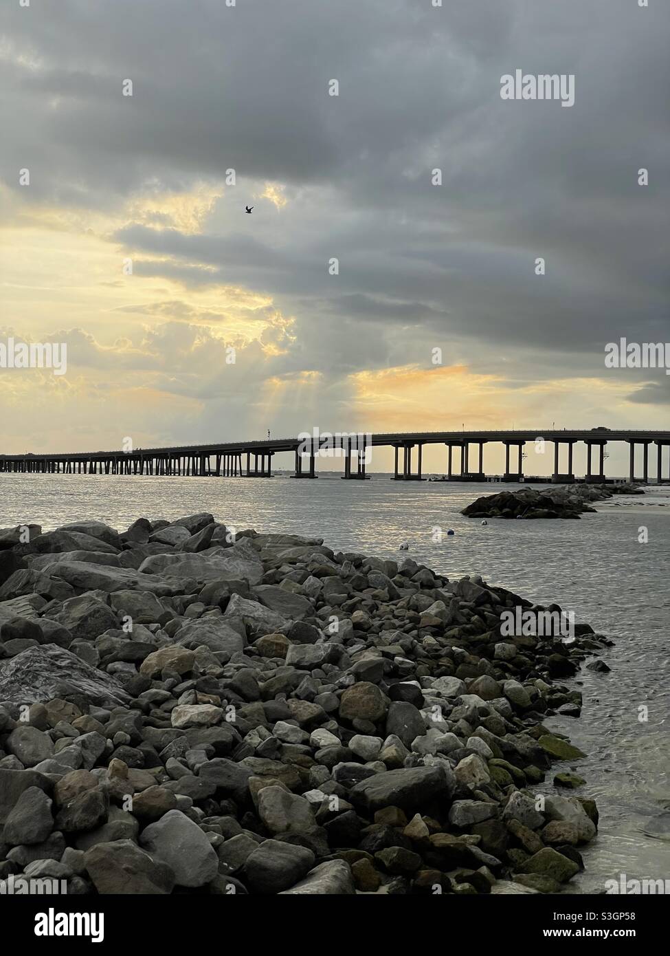 Stormy golden sunset skies over Destin, Florida bridge and Gulf of Mexico water - Smartphone Captured Stock Image