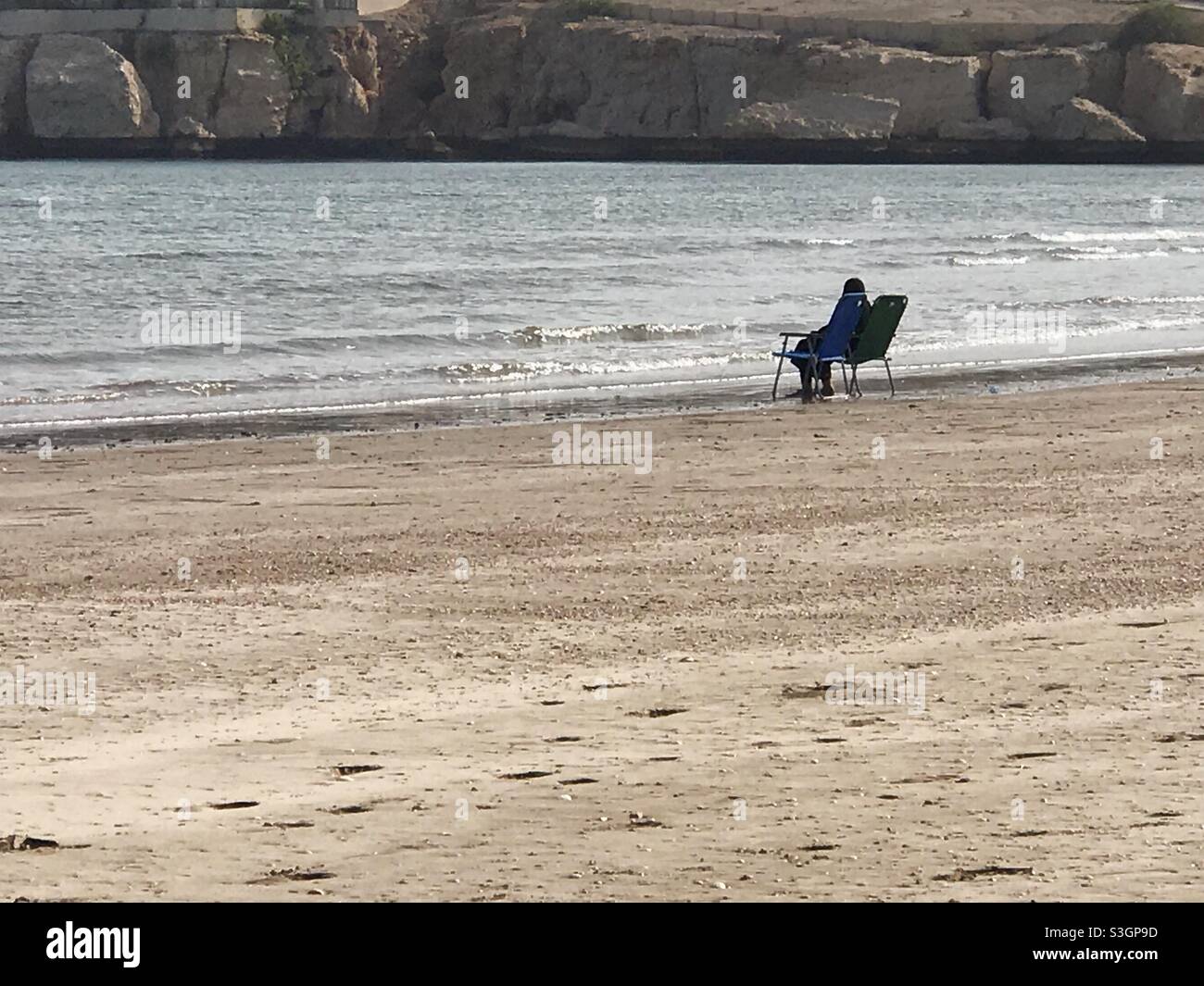 Alone with my thoughts:a woman sitting alone at the beach,watching the horizon - Smartphone Captured Stock Image