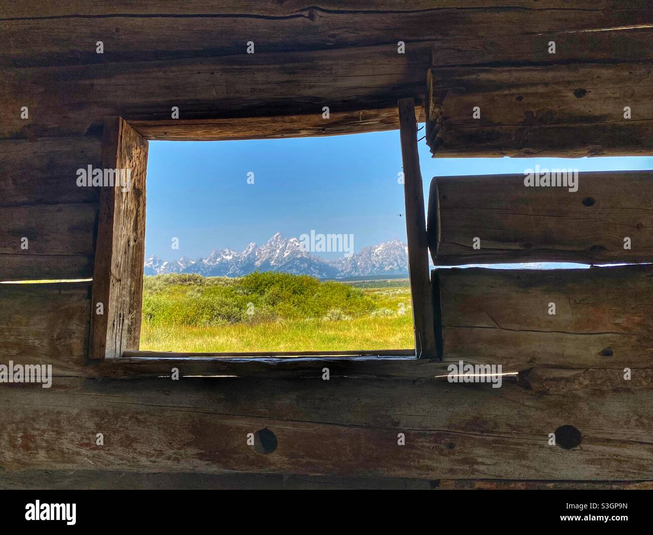 Grand Teton mountains through the window of the Cunningham log cabin Stock Photo
