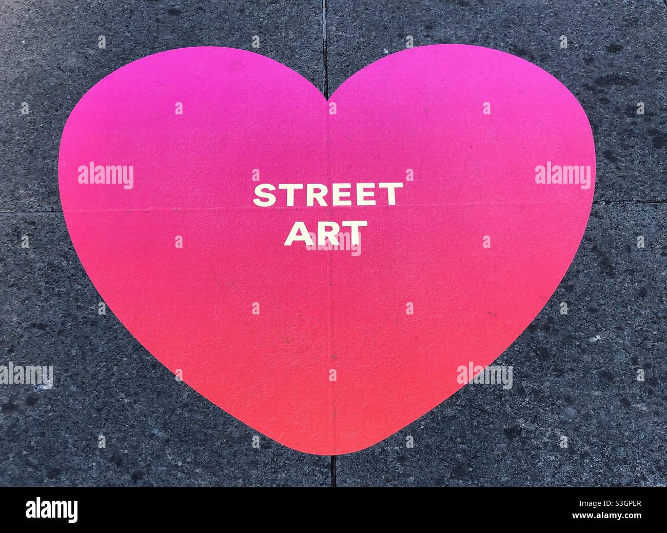 A pink heart sticker on the ground. Stock Photo