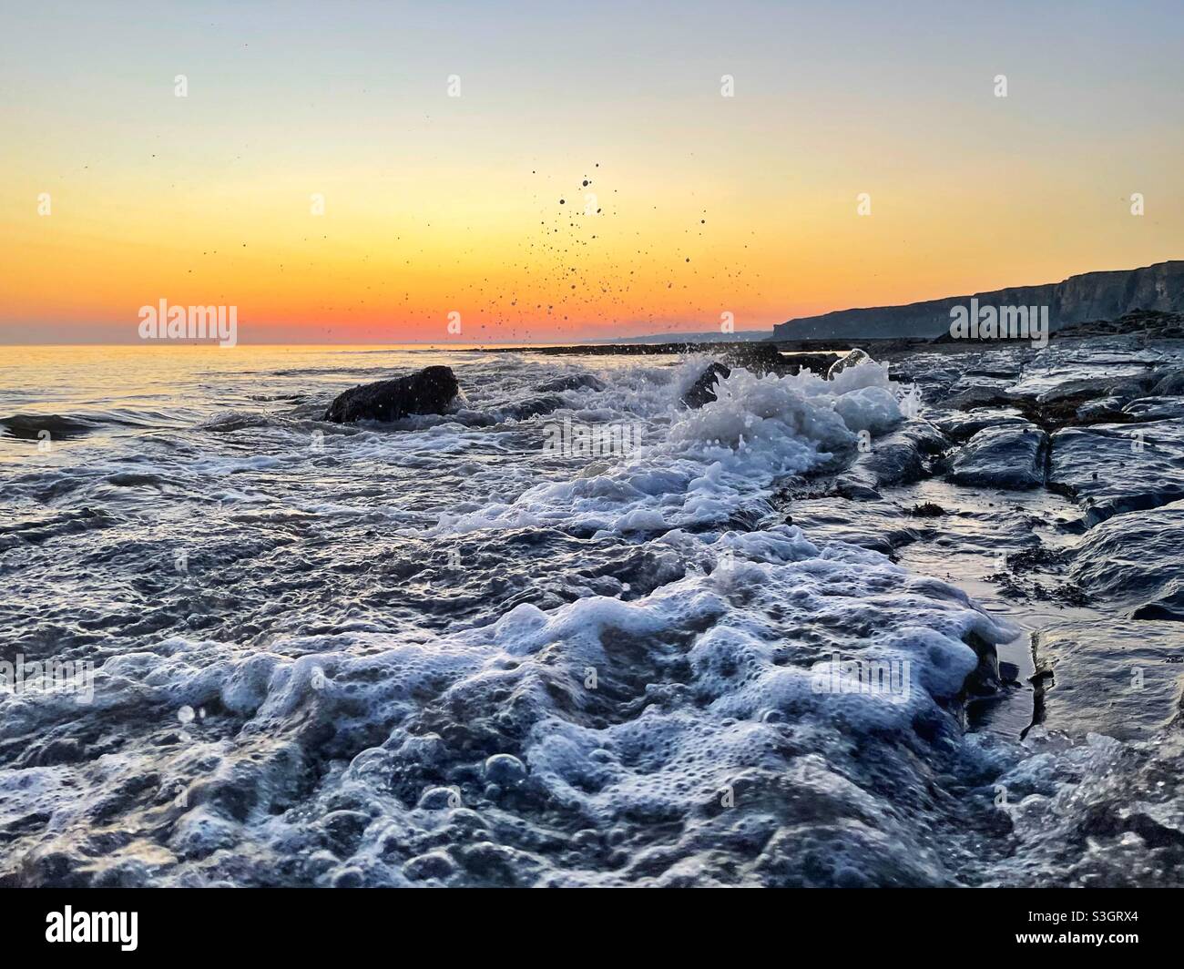 Bubbling sea on the South Wales coast at dusk, incoming tide. Stock Photo