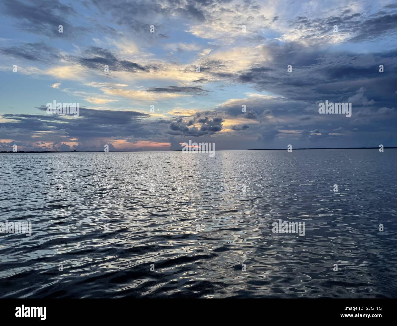 Dramatic sunset clouds over bay water Stock Photo - Alamy