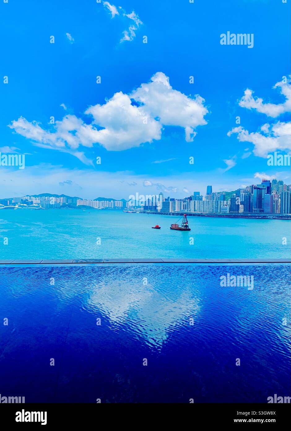 A view of Victoria harbour from the infinity pool of the Rosewood hotel in Kowloon, Hong Kong. - Smartphone Captured Stock Image