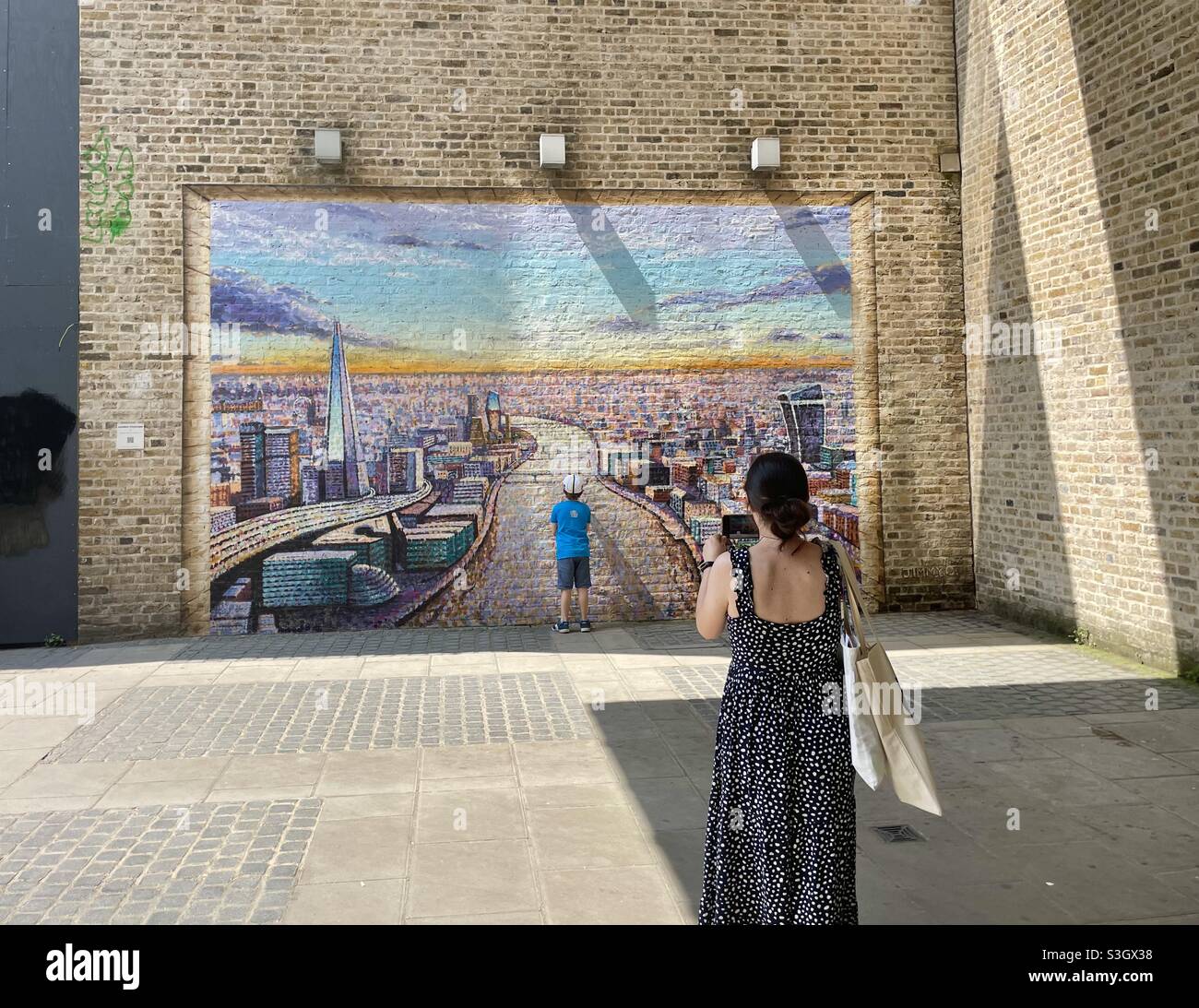 Woman photographic her young sun in front of a moral of london on the south bank Stock Photo