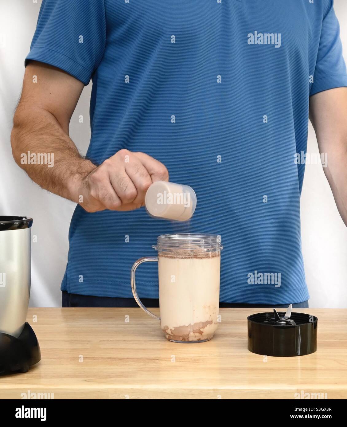 Man in blue shirt Blending chocolate protein shake for fitness - Smartphone Captured Stock Image