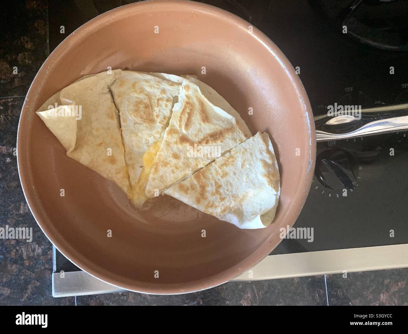 Tortilla with cheese quesadillas on the stove top cooking in a golden