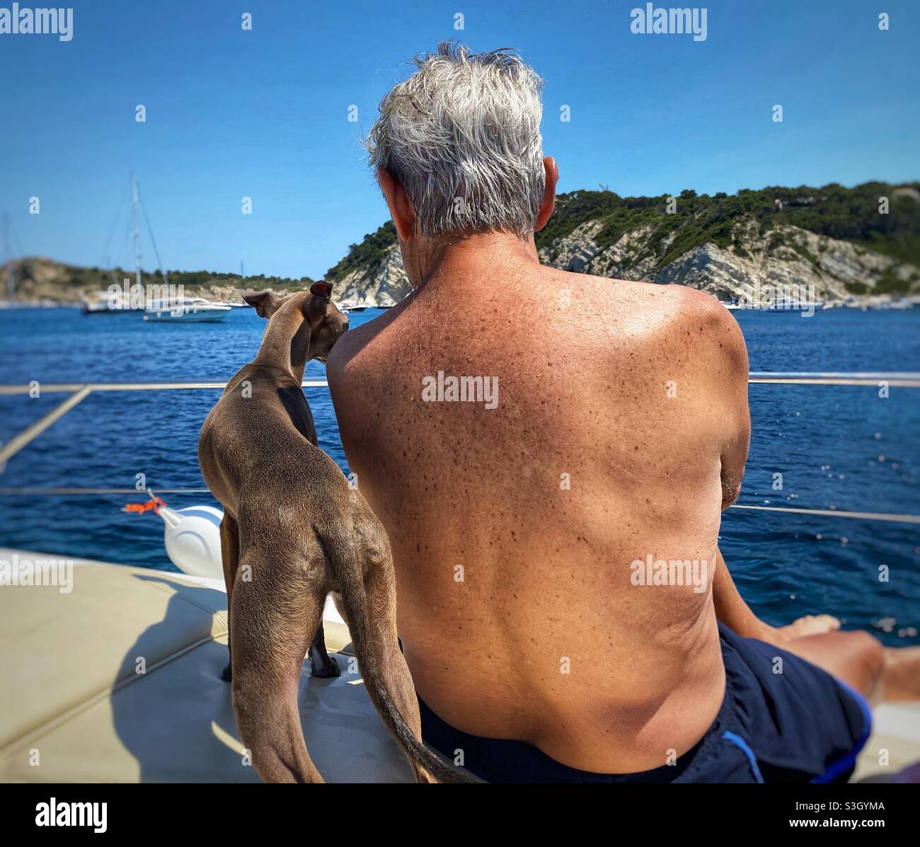 An old man with a dog on a boat in the sea Stock Photo