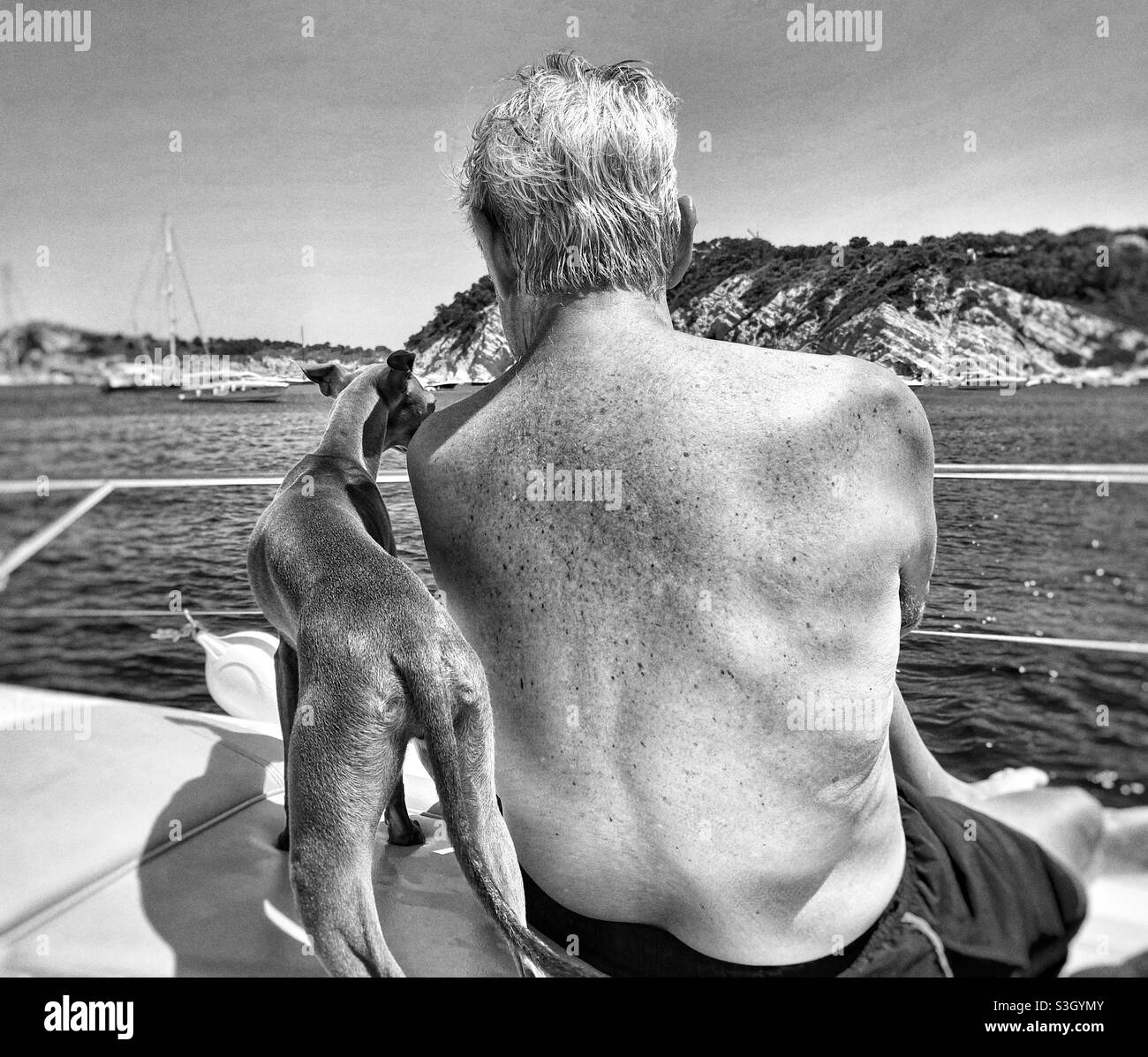Old man with his dog on a boat by the sea Stock Photo
