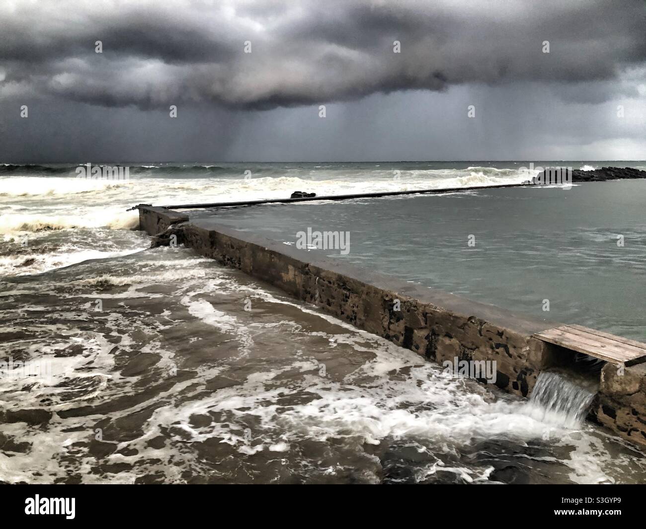 Moody skies and big storm clouds over the Indian Ocean and Thompson’s Bay tidal pool in Ballito, South Africa Stock Photo