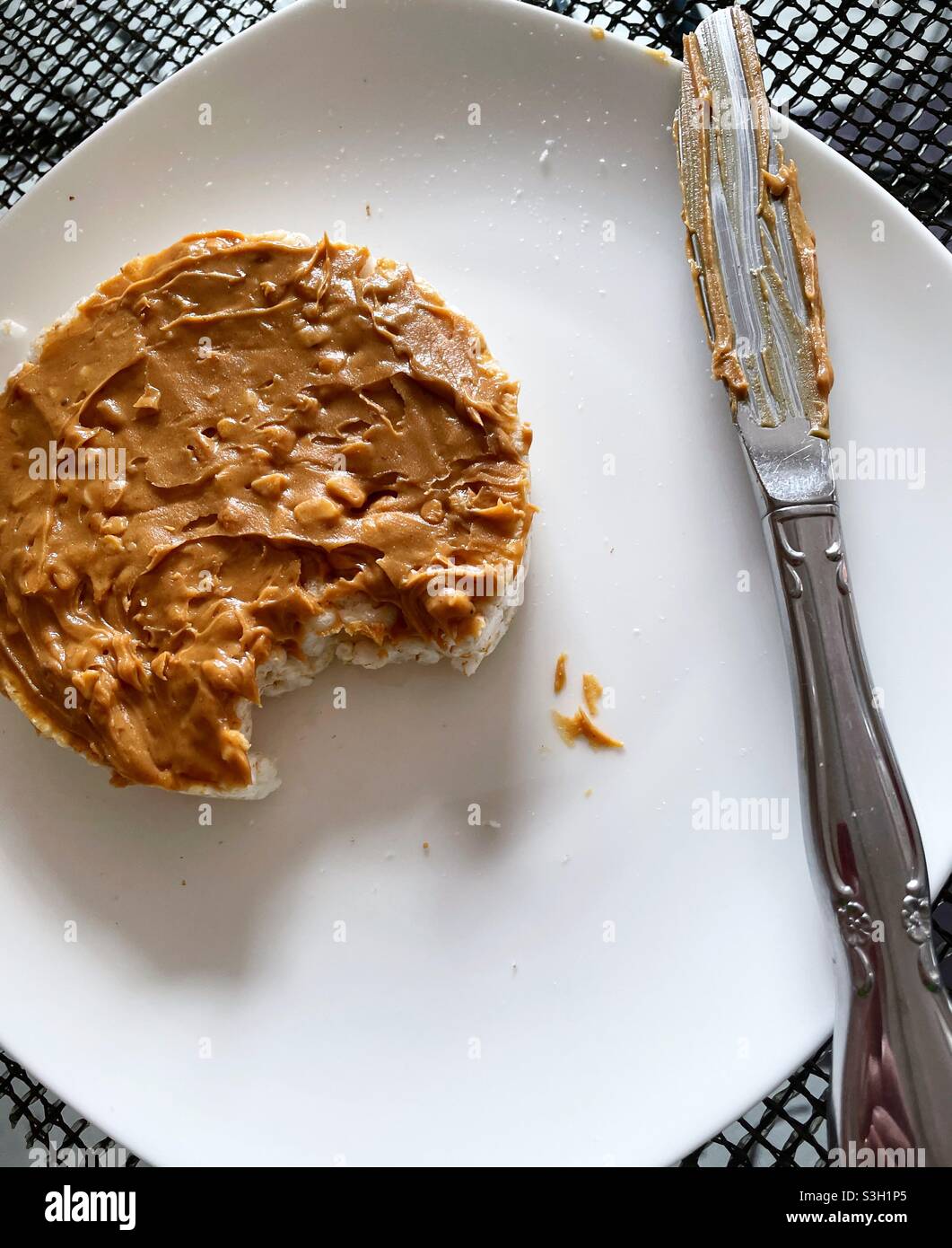 Flatly of a rice cake with peanut butter topping and a bite taken out of it - Smartphone Captured Stock Image
