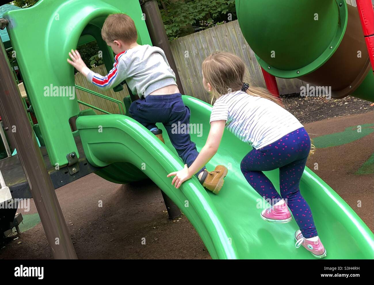 Boy & Girl playing on a slide Stock Photo
