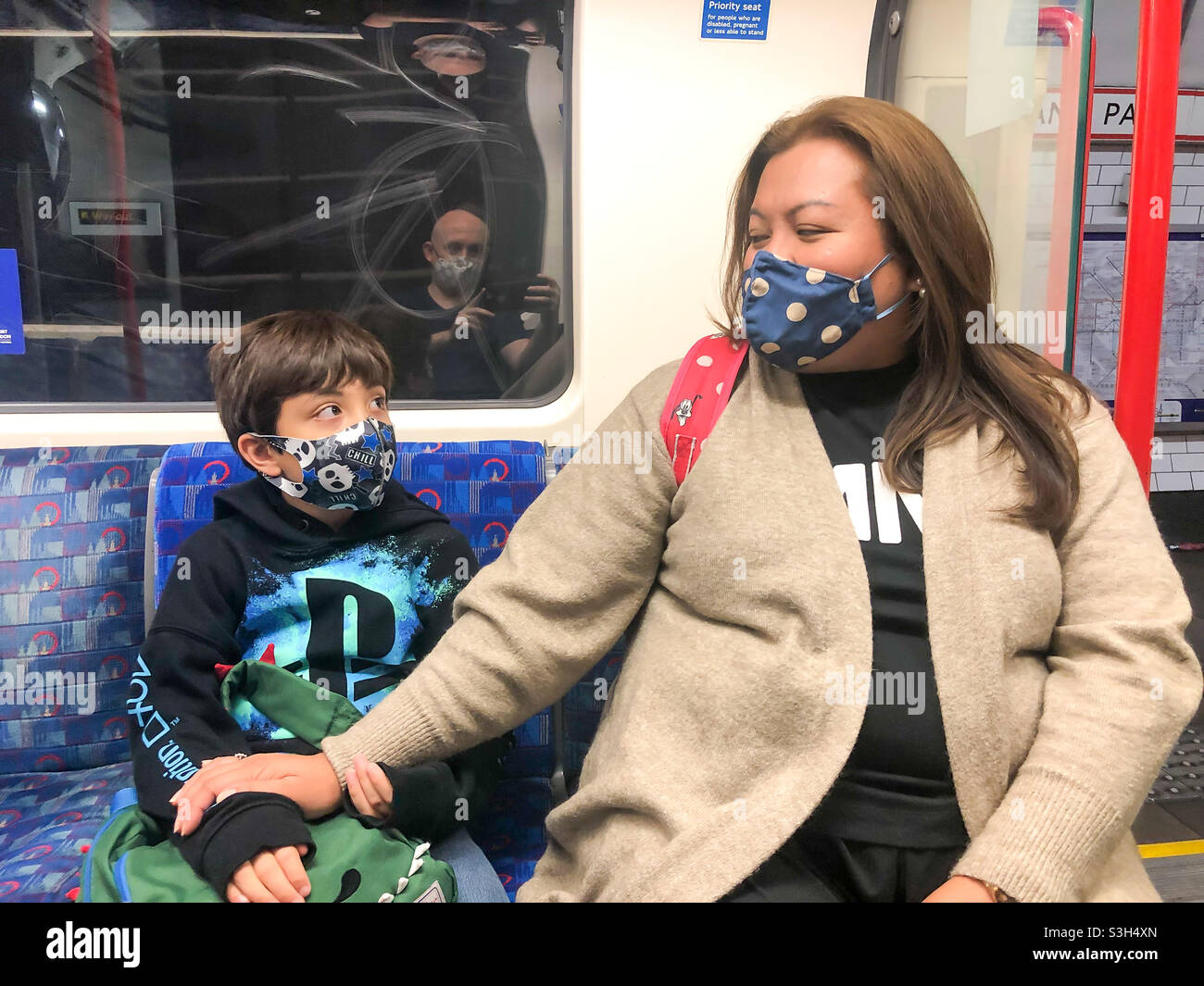 Mother and son wear masks and sit together on a London Underground train. - Smartphone Captured Stock Image
