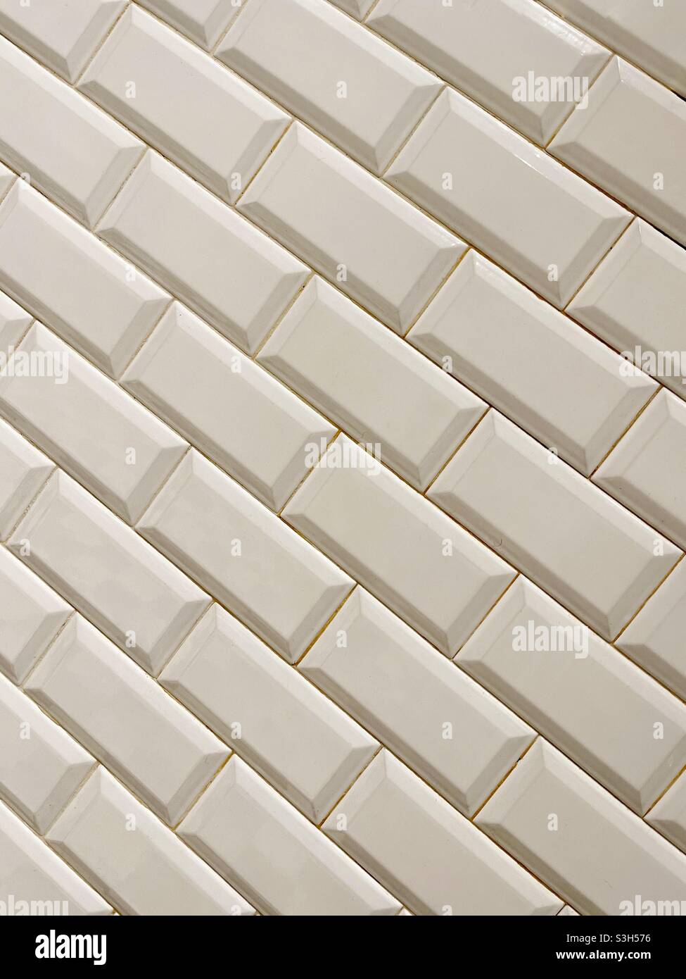 Diagonal pattern of white bevelled tiles on an interior wall Stock Photo