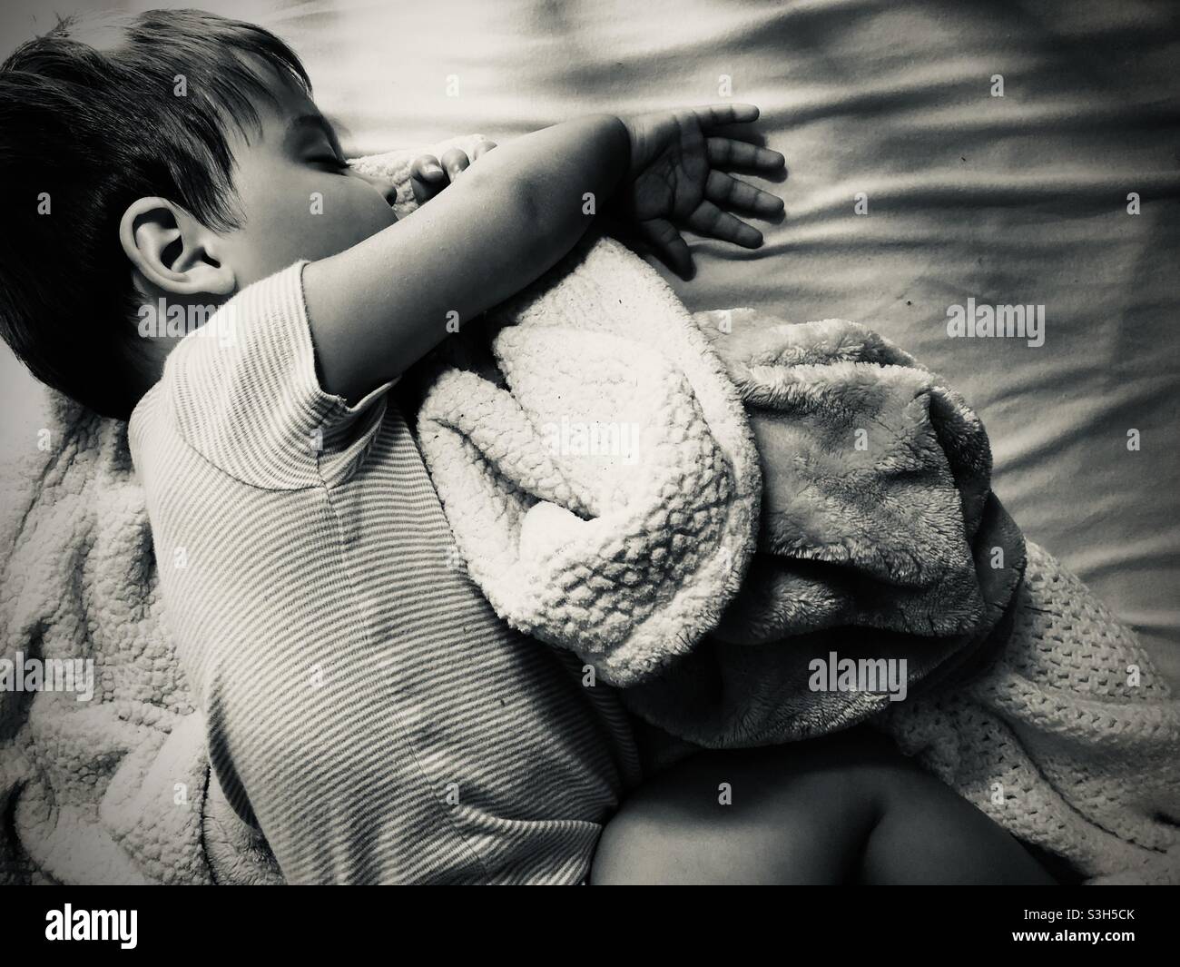 Sleeping baby boy sucking his thumb-horizontal top down view in black and white - Smartphone Captured Stock Image
