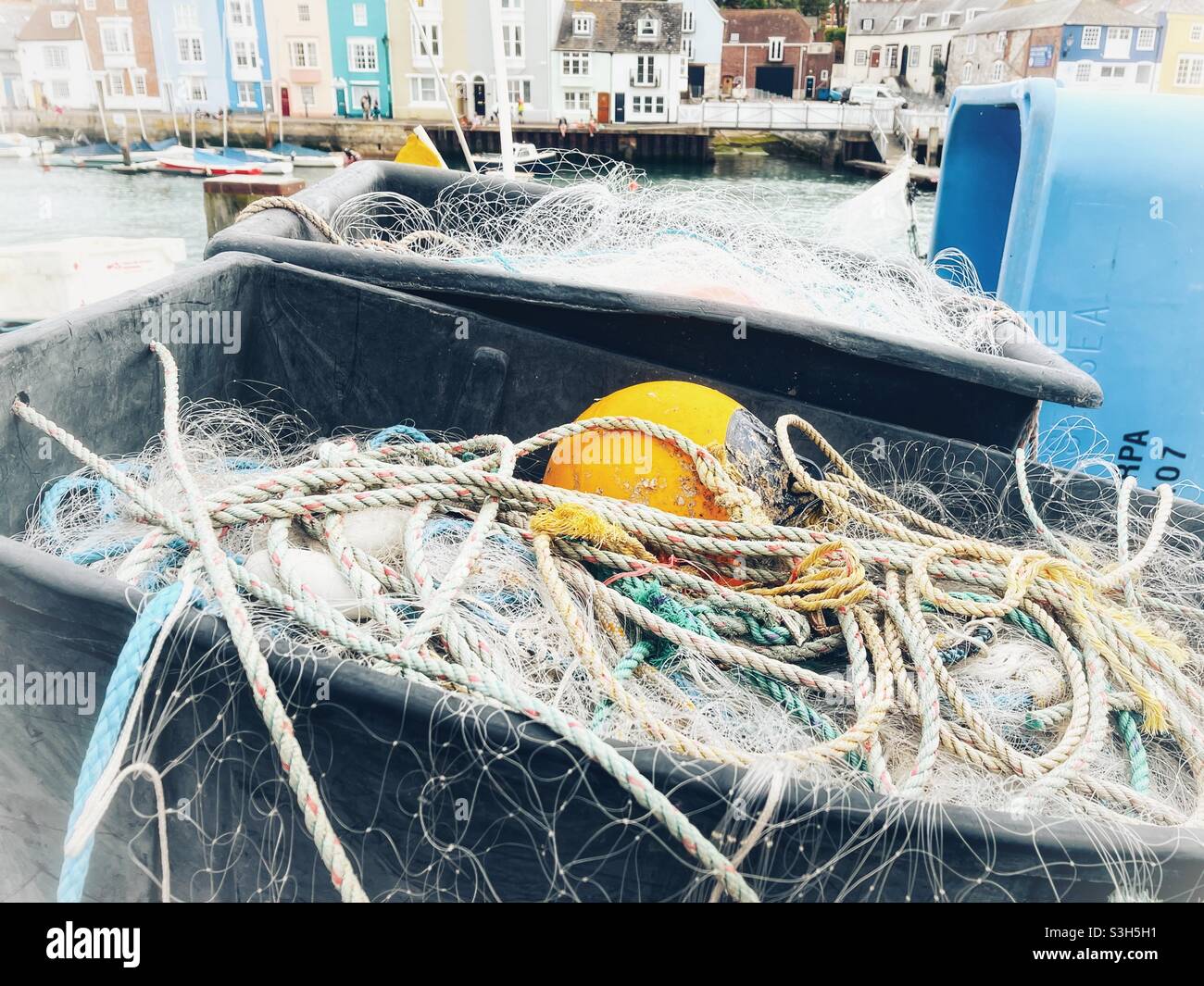 Fishing nets and floats in containers on the quayside of a harbour Stock Photo
