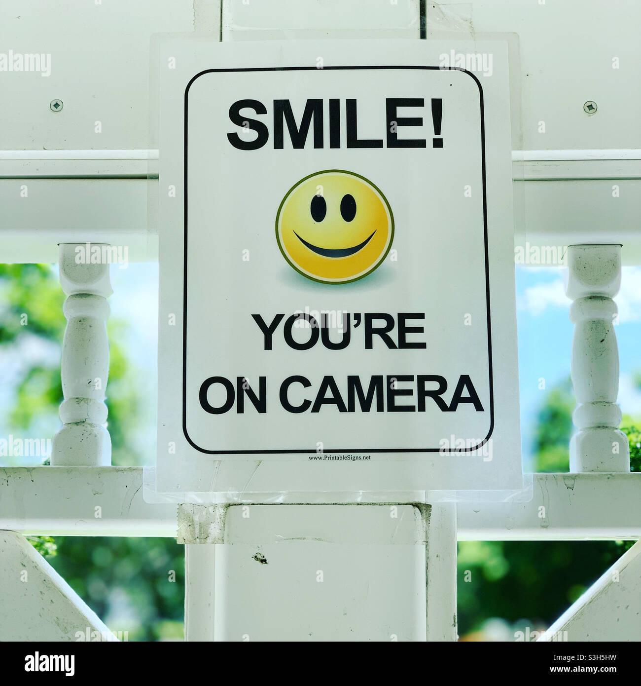 “SMILE! YOU’RE ON CAMERA” sign in an outdoor public area - Smartphone Captured Stock Image