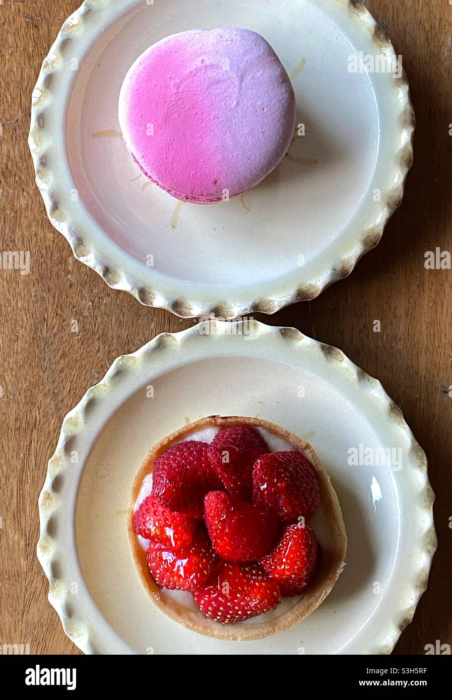 Macaron and strawberry cake on two creamy vintage plates Stock Photo
