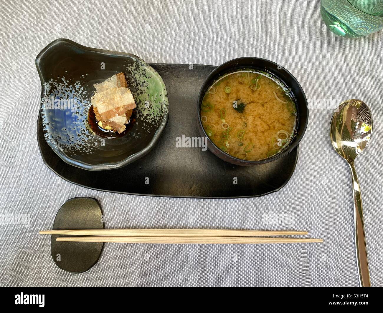Miso soup served in a black bowl with chopsticks and spoon Stock Photo